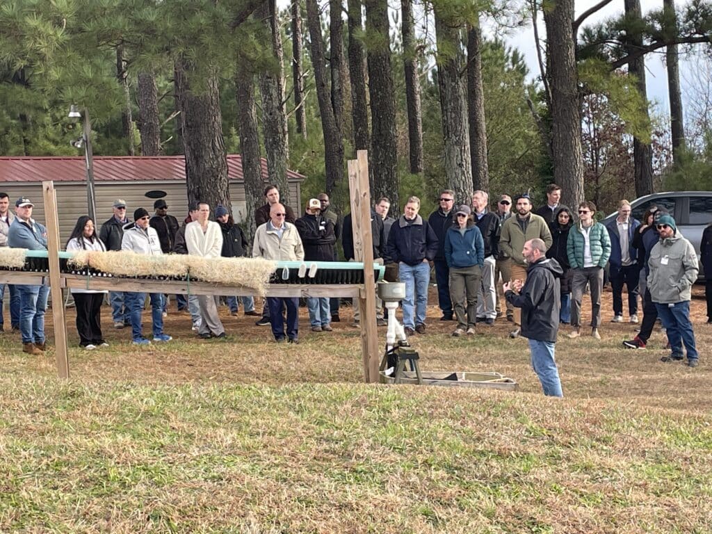 Image shows workshop participants observing a demonstration of turbidity reduction performance of erosion control matting and dewatering bags with and without flocculant treatment.